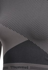 Figurbetontes Sportoberteil in Dunkelgrau mit horizontalen und diagonalen Streifenmustern. Bietet einen weichen, strukturierten Stoff und ein gebrandetes Bündchen am unteren Ende.