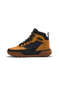 Botas de senderismo de caña alta con cuero marrón, detalles en tela negra, suela marrón resistente, ojetes de metal y asa en el talón. Marca de impermeabilidad visible.