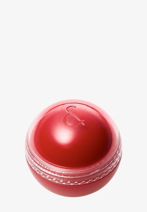 Rund rød læbepomadebeholder med gennemsigtigt bånd omkring midten og præget ampersand-symbol på toppen.