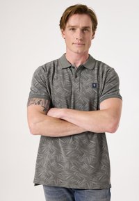 Grijze polo met een subtiele bladvorm, korte mouwen en een kraag. Bevat een logo op de linkerkant van de borst. Draag het met blauwe jeans.