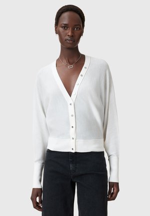 Cardigan bianco con scollo a V, caratterizzato da sette bottoni argento sulla parte anteriore. Realizzato in un tessuto leggero con polsini e orlo a costine.