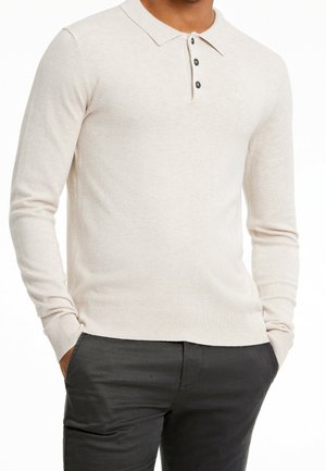 Polo à manches longues en tissu tricoté beige clair, avec un col, une patte de boutonnage à trois boutons et un ourlet côtelé. Sans motifs ou accents visibles.
