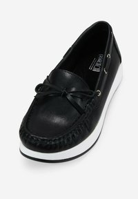 Zapato de mocasín negro de piel con punta redonda, suela de goma blanca, cordones decorativos y detalles de costura a lo largo del borde.
