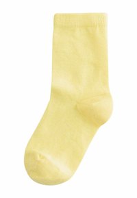 Vienas šviesiai geltonos spalvos kulkšnies kojinė, parodyta išskleista, su raštuotu apvadu ir lygiu mezgimu, ant balto fono.