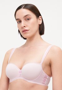 Helles rosa BH mit gepolsterten Cups und Spitzenakzenten. Verfügt über verstellbare Träger und ein Netzband. Glatte Textur mit zarten Details.