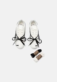 Białe sneakersy z czarnymi akcentami, z gładką skórzaną powierzchnią, zaokrąglonym noskiem i czarnymi sznurowadłami. W zestawie dodatkowe sznurowadła w kolorze czarnym i białym.