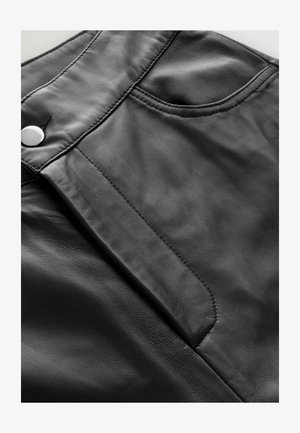 Sort lædernederdel med en glat overflade, frontlomme og en sølv snap-lukning nær taljen. Enkel og nedtonet design.