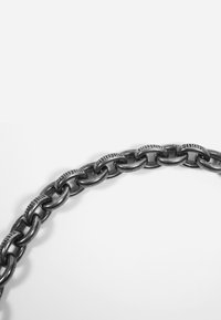 Metallkjede med store, sammenkoblede ledd i en mørk finish. Tekstdetaljer er synlige på utvalgte ledd.
