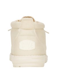 Botas de tobillo de lona beige con punta redondeada, tejido texturizado y suela de goma que presenta un logotipo moldeado en la parte trasera.