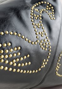 Zwarte leren tas met een decoratief ontwerp van gouden studs, met een gestructureerde afwerking en afgeronde studs die het oppervlak accentueren.