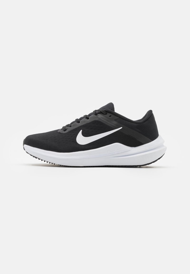 Chaussure de running Nike noire basse avec logo swoosh blanc et semelle blanche épaisse, vue de profil sur un fond uni.