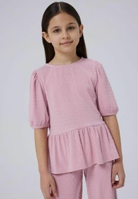 Helles rosa Oberteil mit strukturiertem Muster, kurzen Puffärmeln und Peplum-Design, kombiniert mit passenden strukturierten Hosen. Glatte Stoffoberfläche.