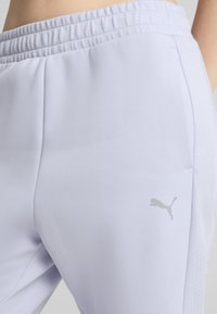 Šviesiai levandų spalvos sportinės kelnės su elastingu juosmeniu, turinčios tekstūrines šonines dalis ir mažą atspindinčią logotipą kairėje šlaunyje.