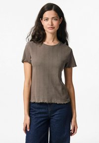 Ruskona raidoitettu lyhythihainen t-paita, jossa on pyöreä kaula-aukko, sahalaitainen helma ja rispaantuneet hihansuut, yhdistettynä tummansinisiin farkkuihin.