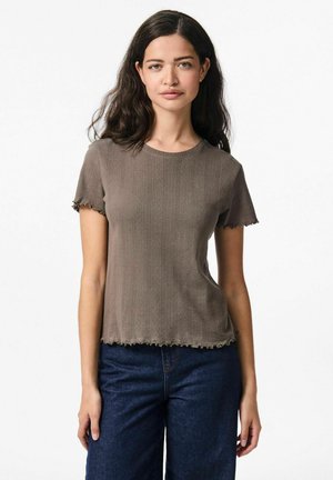 T-shirt a maniche corte a coste marrone con scollatura rotonda, orlo frastagliato e bordi delle maniche sfilacciati, abbinato a pantaloni in denim blu scuro.