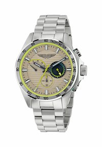 Sudraba nerūsējošā tērauda pulkstenis ar bēšu teksturētu ciparnīcu, zaļiem akcentiem, tachymeter bezeli un trim subciparnīcām ar atšķirīgiem rādītājiem.