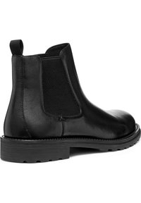 Botas Chelsea de cuero negro con paneles elásticos en los laterales, punta redonda y suelas de tracción de goma. Cuenta con una lengüeta en la parte trasera para facilitar su colocación.