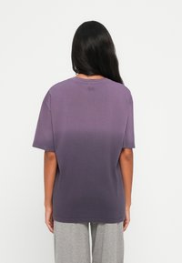 Purpura gradient t-kreklu ar īsām piedurknēm, apaļu kakla un mazu logotipu aizmugurē. Mīksts kokvilnas audums, brīvs piegriezums.