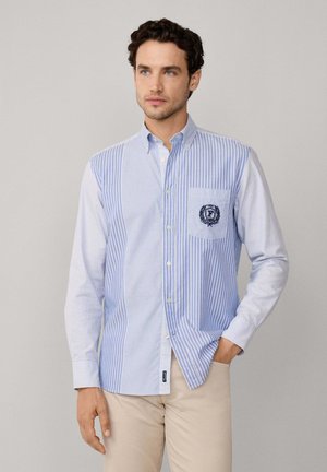 Camicia a maniche corte a righe blu e bianche, con taschino sul petto decorato con un logo ricamato e colletto con bottoni. Materiale in cotone.