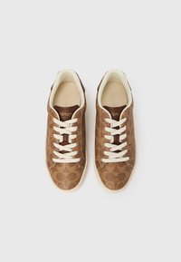 Baskets en cuir marron avec un motif texturé, lacets crème, bout arrondi et semelle beige ; avec le logo de la marque sur la languette.