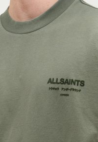 Φούτερ σε ελιά πράσινο με ριμπ λαιμόκοψη, διακοσμημένο με κεντημένο λογότυπο "ALLSAINTS" και ιαπωνικό κείμενο στο μπροστινό μέρος.