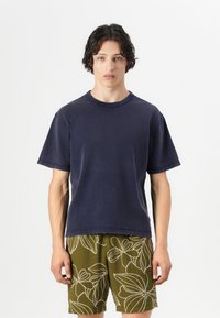 Navy cotton t-shirt with a crew neck and short sleeves, paired with olive green shorts featuring white floral patterns.