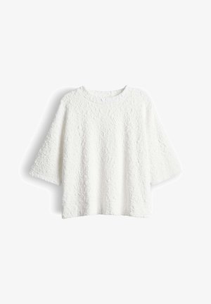 Witte textuur lange mouwen shirt met een ronde hals en licht uitlopende mouwen, plat weergegeven tegen een witte achtergrond.