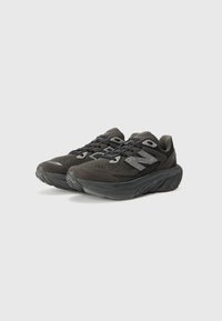 Baskets de sport noires avec une tige en mesh texturé, col rembourré et semelle en caoutchouc épaisse. Présente des accents réfléchissants et un système de laçage.