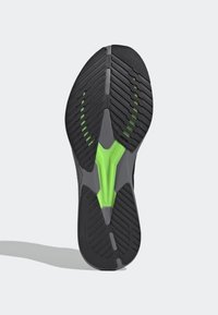 Suola di scarpa in gomma nera con motivo a spina di pesce e un accento verde nella suola intermedia. Presenta un design sagomato per una buona aderenza e stabilità.