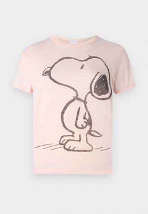 Henkilö pukeutunut vaaleanpunaiseen Snoopy-paitaan, löysiin mustiin nahkahousuihin, mustiin sandaaleihin ja pitää mustaa tekstuuripintaa olevaa clutch-laukkua.