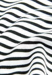 Tissu noir et blanc avec des rayures alternées, présenté en douces vagues repliées qui créent de la profondeur et de la texture.