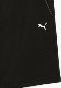 Sorte atletiske shorts lavet af blødt stof, med et hvidt Puma-logo og kontrasterende side-striber i rød og blå.