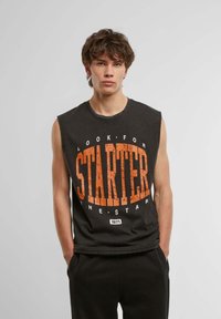 Black sleeveless t-shirt featuring a distressed orange "STARTER" graphic and text design. Fabric appears soft with a relaxed fit.