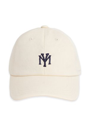 Jonge man met een beige pet met donker logo, lichtblauwe patroonige neksjaal, wit geribd shirt met logo en een donkere jas over de schouders gedrapeerd.