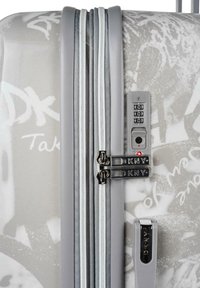 Maleta de concha dura con un acabado blanco brillante, decorada con patrones de graffiti en gris, cierre de doble cremallera, cerradura combinada y acentos de hardware de marca.