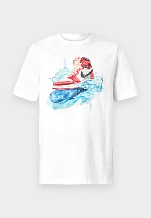 T-shirt bianca con una grafica colorata di scarpe da ginnastica rosse e nere sopra spruzzi d'acqua blu stilizzati. Collo rotondo, maniche corte, vestibilità standard.