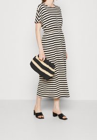 Mustavalkoraidallinen midimallinen mekko, jossa on lyhyet hihat, joustava vyötärö ja sileä kangas. Yhdistetty tekstuurilla varustettuun mustavalkoraidalliseen clutch-laukkuun.