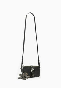 Mustast nahast ristikott lillemustriga, tõmblukk, reguleeritav rihm ja hõbedased metalldetailid. Minimalistlik disain.