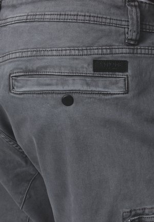 Grijze denim broek met een standaard achterzak, knoopdetail en een merklabel in het zwart. Het materiaal heeft een gladde, licht gestructureerde afwerking.