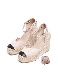 Beige suède espadrille-wedges met zwarte neus, gevlochten jute zool en enkelbandje. Inclusief bijpassende stoffen band in beige.