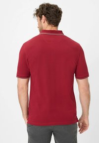 Rød polo shirt med korte ærmer, der har et ensfarvet design, ribbet krave og kontrastfarvet hvid syning på ærmesømmene.