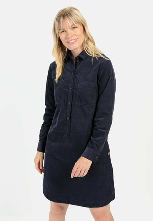 Marineblauwe corduroy jurk met lange mouwen, knoopsluiting aan de voorkant, twee borstzakken en zijaccenten. Heeft een ontspannen pasvorm en een rechte zoom.