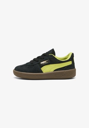 Sorte ruskinds sneakers med limegrønne detaljer, der har en struktureret brun gummisål og sorte snørebånd. Puma-branding er til stede på siden.