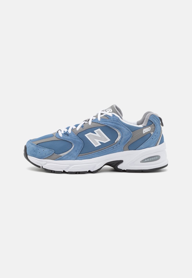Chaussure de course en daim bleu et maille avec des accents gris, des lacets blancs et une semelle en caoutchouc noire. Présente le logo "N" et le marquage "ABZORB".