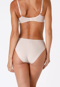 Reggiseno beige e mutandine a vita alta realizzate in tessuto morbido. Il reggiseno presenta spalline regolabili e una chiusura a gancio sul retro.