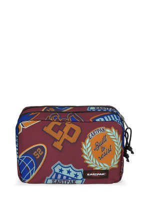 Red fabric pouch with various patches and logos. Features two zippers and a textured surface. Branding on the front includes "Eastpak" and "Built to resist."