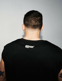Czarny bezrękawnik z małym białym logo na górnej części pleców. Materiał wydaje się gładki i ma matowe wykończenie.