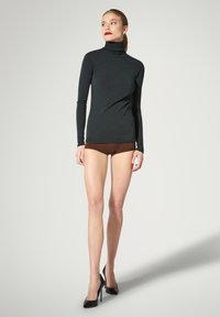 Maglia a collo alto nera a maniche lunghe abbinata a pantaloncini marroni. Il modello indossa scarpe nere con tacco alto, che mostrano un design aderente e liscio.