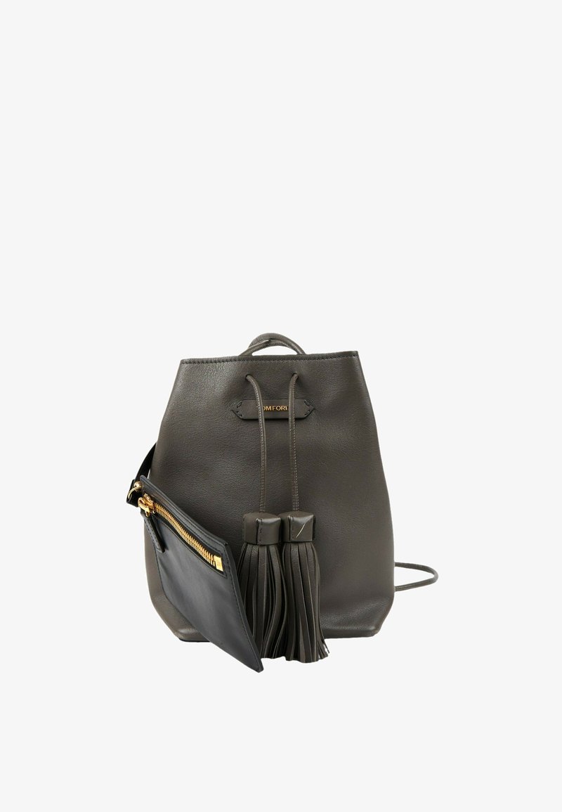 Sac à dos en cuir noir avec cordon, deux pompons et une petite pochette noire attachée avec une fermeture éclair dorée.