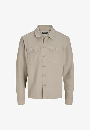 Camicia beige con bottoni realizzata in tessuto testurizzato, caratterizzata da un collo e due taschini sul petto, e maniche lunghe con polsini a bottone.